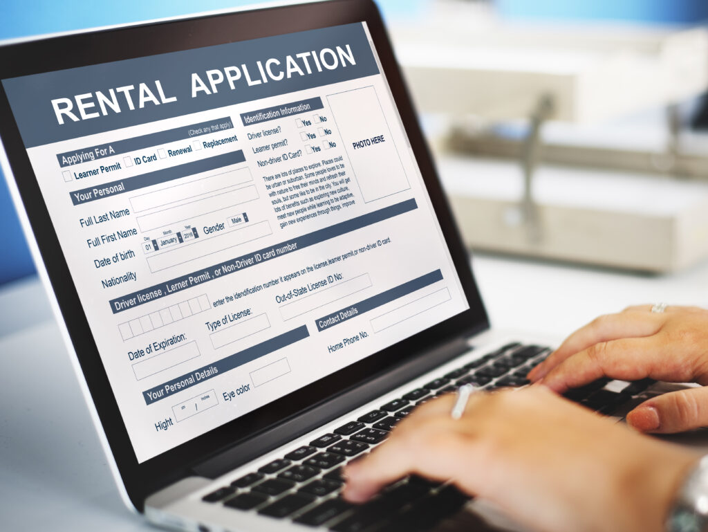 First-time renter without credit reviewing apartment application documents and proof of income on a laptop.