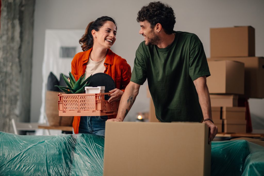 Renters moving into their rent-to-own home and carrying boxes into their new place.